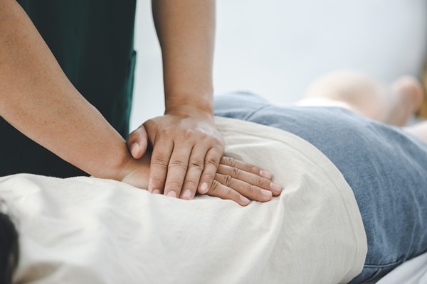 Chiropractor performing a lower back massage on patient