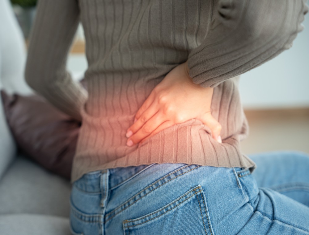 Woman holding her lower back while in pain. Concept for lower back pain chiropractor help.