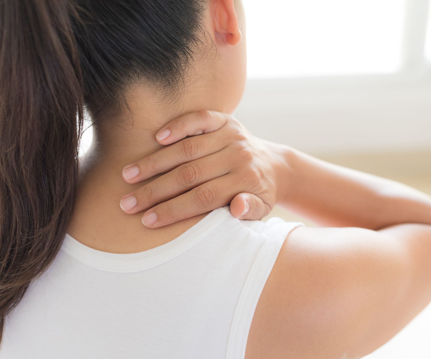 Woman holding her neck in pain. Concept for help from a chiropractor for neck pain.